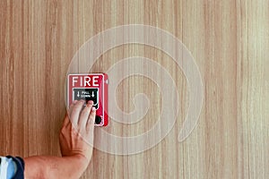 The hand of man is pushing fire alarm on the wall. Hand of man pushing fire alarm switch on the white wall as background for emerg