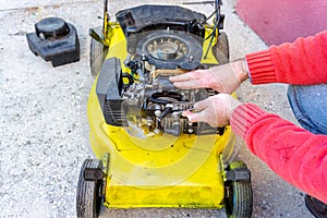 Hand of man repairing old grass cutter with tools on cement floor. Repairing lawn mower engine