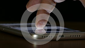 Hand of a man searching on a touch screen smartphone in the dark