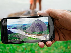 Hand of a man showing a landscape photo of the guainia river taken with a smartphone photo