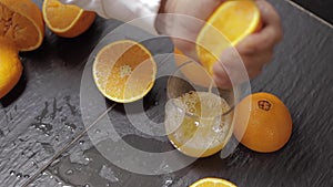 Hand of man squeeze juice from an orange into glass. Man hold half of orange on hand