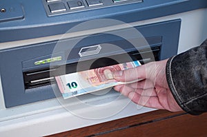 Hand of man taking money at the automated machine of