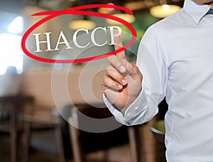 Hand of man touching text HACCP with white color on blur interior background.