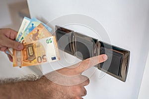 Hand of man turning on the light and with euro banknotes representing the high cost of inflation.