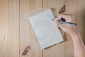 Hand of man use pencil writing `TO DO LIST` on white notebook on wooden table