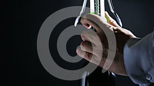 Hand man using corkscrew to open a bottle of wine. Black background