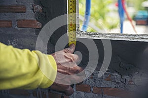 Ã Â¹â¡Hand of man using tape measure window with brick wall background. Construction Workers work at construction site.  Worker work