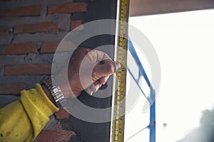 Ã Â¹â¡Hand of man using tape measure window with brick wall background. Construction Workers work at construction site.  Worker work