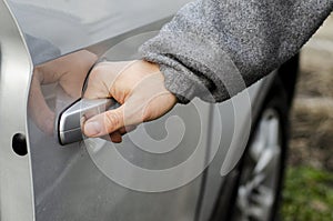 The hand of a man in warm clothes opens the car door