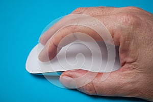 Hand of man on white mouse on blue background