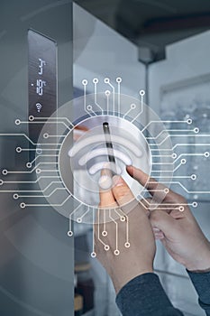 The hand of the man who controls the refrigerator with his smartphone. Internet of Things Concept