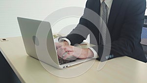 Hand of man working on laptop computer on desk at home, male typing on notebook.