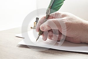 Hand of a man writing a letter or note with a pen and black ink