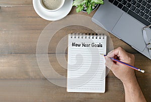 Hand man writing New year goals on note paper