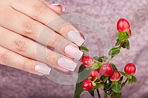 Hand with manicured nails colored with beige nail polish