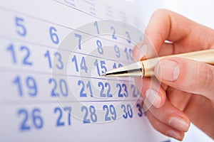 Hand marking date 15 on calendar photo