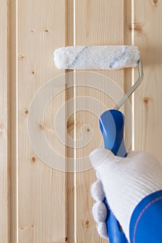 Hand of the master , applies protective impregnation to the wooden surface, roller, close- up