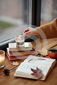 hand with match lighting candle on window sill