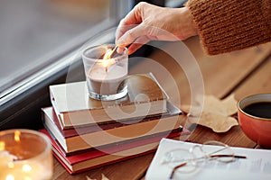 hand with match lighting candle on window sill