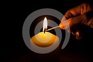 Hand with matchstick, lighting a candle