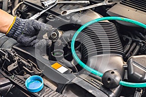 Hand of Mechanic check water in car radiator and add water antIfreeze coolant fluid to car radiator at garage , service and photo