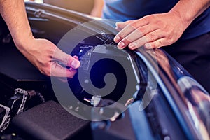 The hand of a mechanic is checking the connectors of car engine. Checking the engine by yourself