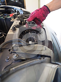 Hand of mechanic man with the engine service or repair in an automotive workshop;