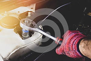 Hand of mechanic man with red glove has using socket wrench for repairing engine of a car