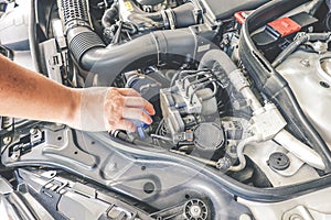 Hand of mechanic is repairing car engine working in garage