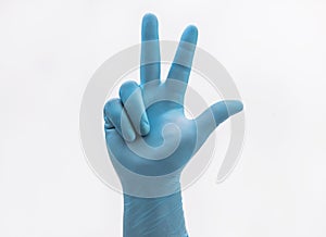 Hand with medical blue latex protective gloves showing three fingers on white background
