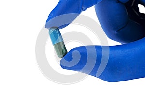 Hand with medical glove holding pill