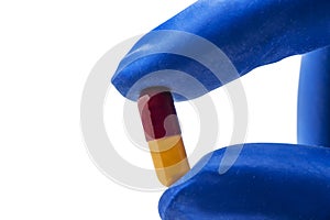Hand with medical glove holding pill
