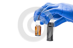 Hand with medical glove holding pill bottle