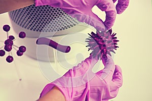 A hand in a medical glove holds the flu virus in the laboratory, concept. Search for a vaccine for coronavirus disease, white