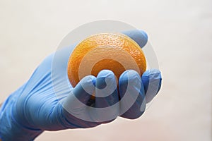 Hand in medical glove holds an orange - vitamin, coronavirus, covid19