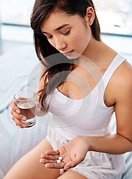 Hand, medicine and water with woman in bedroom of home from above for prescription, supplement or vitamins. Healthcare