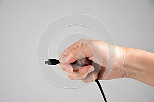 Hand and micro usb cable  white background.