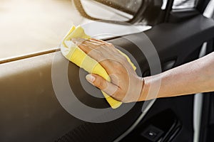 Hand with microfiber cloth cleaning interior car door