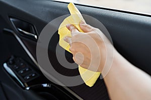 Hand with microfiber cloth cleaning interior car door