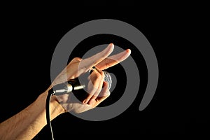Hand with microphone and devil horns isolated on black