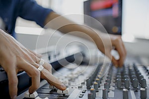 Hand on a mixer, operating the leader. Sound engineer working at mixing panel in the recording studio. Hands adjusting