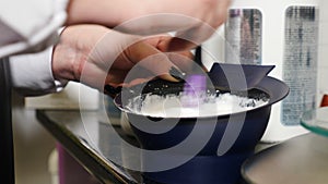 Hand mixing hair dye color in plastic bowl in beauty salon. Hairdresser prepares foam for dyeing hair with pigment in