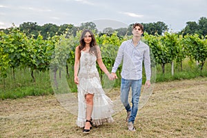 Hand in hand, the model couple swagger through the vineyards in the countryside photo