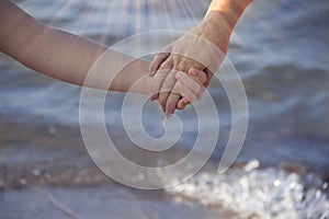 Hand of mom and baby  closeup  on the background of the sea