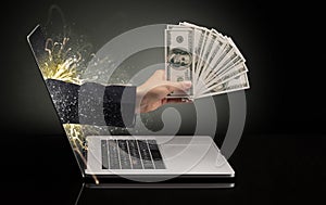 Hand with money  coming out of a laptop