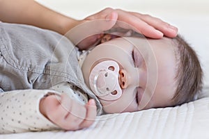 Hand of mother caressing her baby girl sleeping