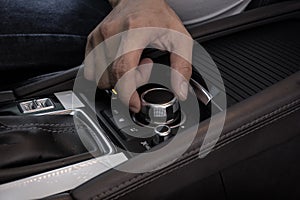 Hand on multimedia control buttons of a modern car