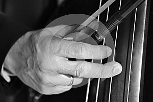 Hand of a musician playing on a contrabass closeup Black and white image