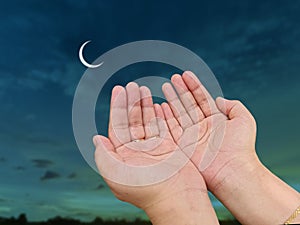 Hand of Muslim women praying with sky moon background.
