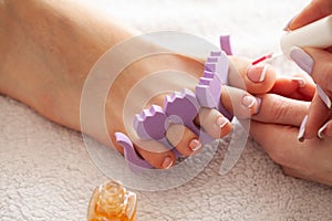 Hand and Nail Care. Beautiful Women`s Feet with Pedicure in Beauty Salon. The Master Applying on Nail. Spa Manicure.